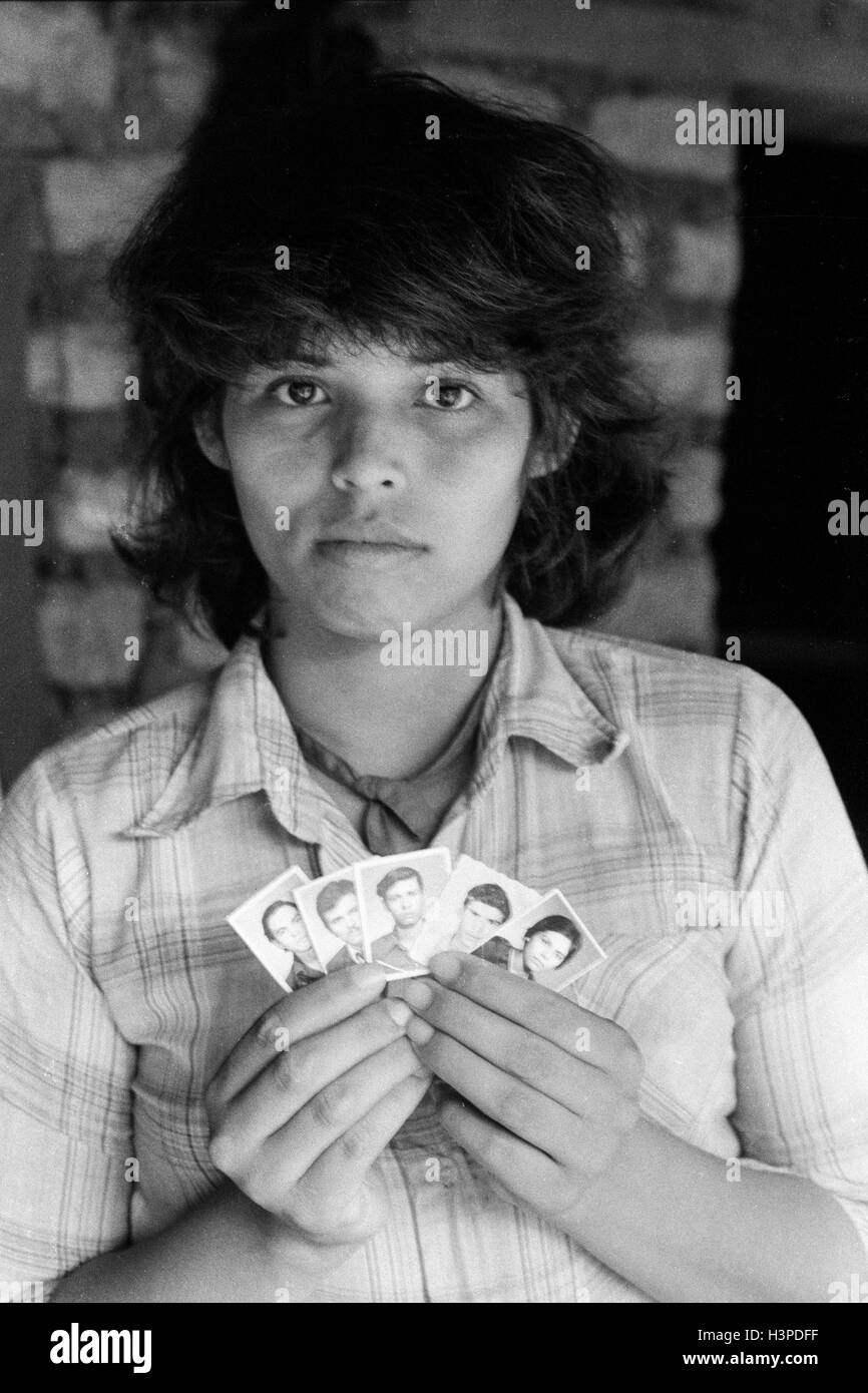 CHALATENANGO,  EL SALVADOR, FEB 1984: - Within the FPL Guerrilla's Zones of Control  - Teresa de Jesus Serrano aged 22, with the pictures of her four brothers and her husband who all died during in the war at 22. Stock Photo