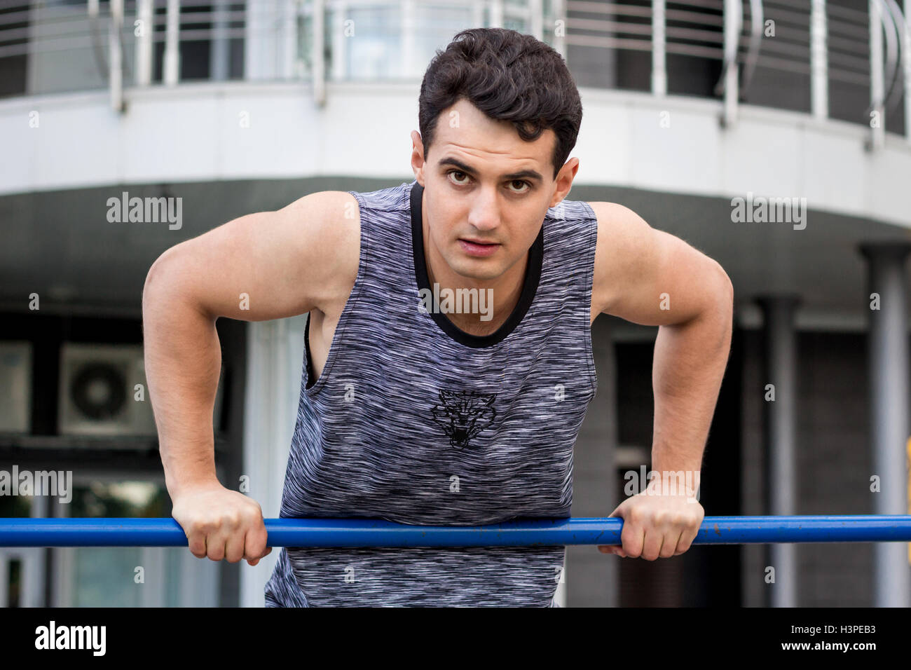 Young fitness man lifts up on horizontal bar during training workout outdoor Stock Photo