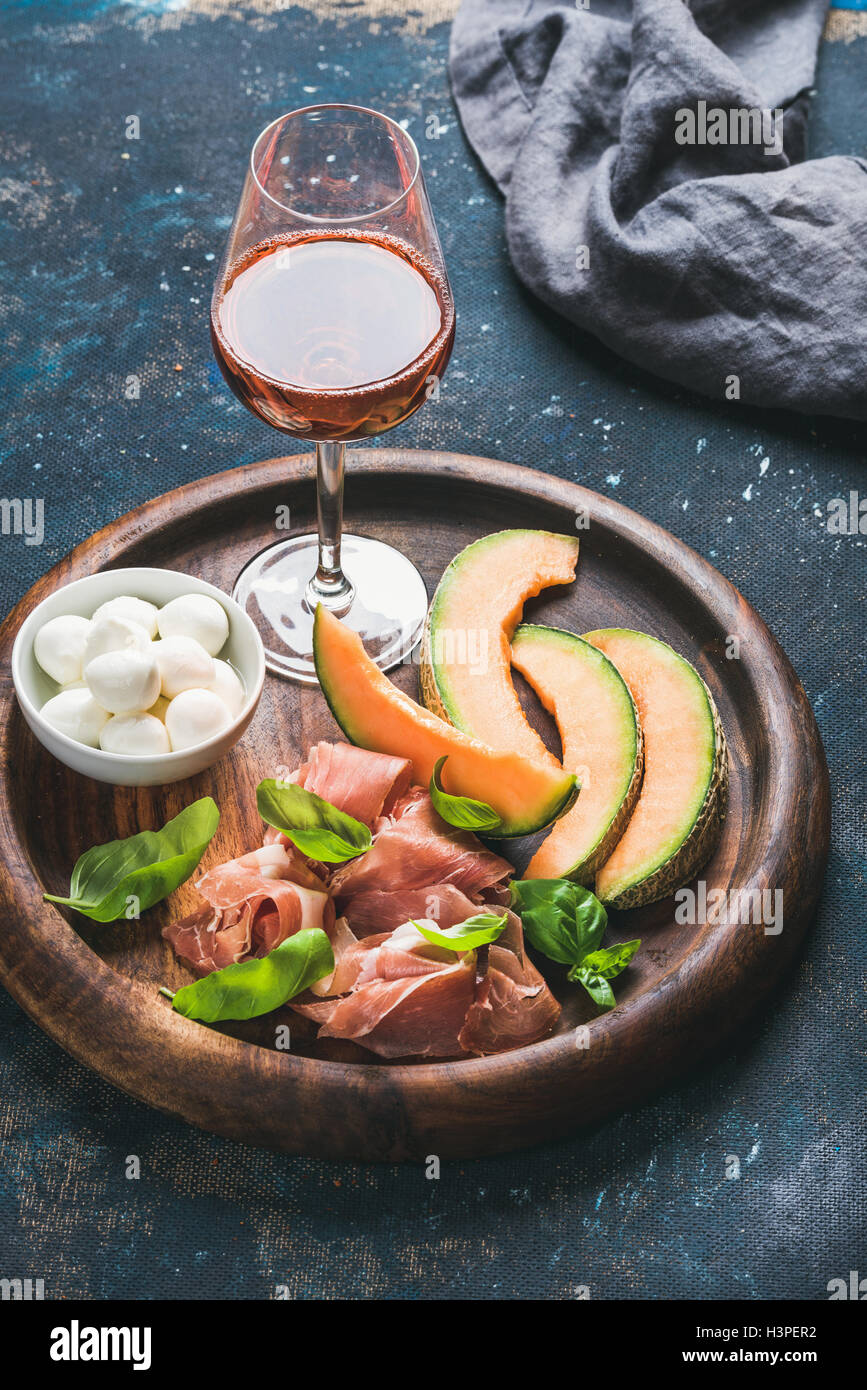 Prosciutto, cantaloupe melon, mozzarella cheese and glass of rose Stock