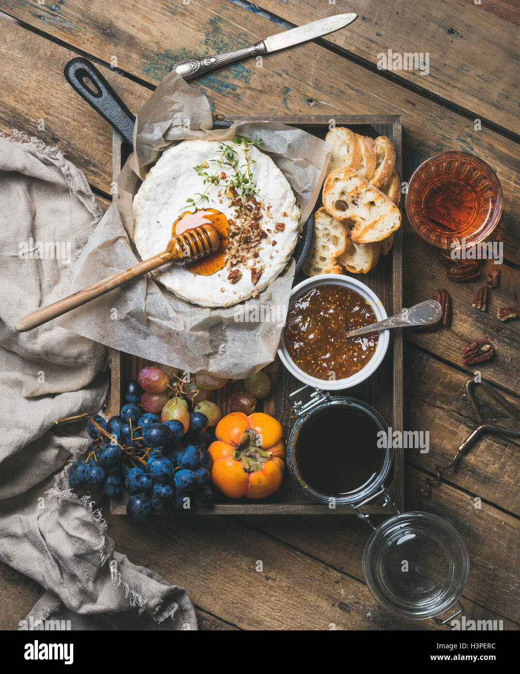 Camambert with honey, nuts, herbs, fruits and rose wine Stock Photo