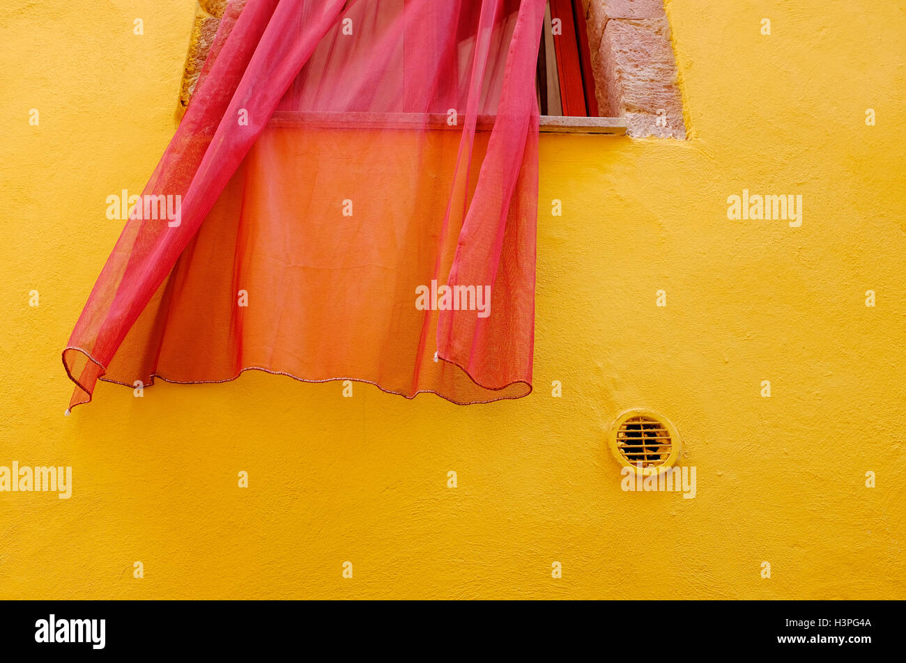 red net window curtain on yellow painted wall in bosa, sardinia, italy Stock Photo