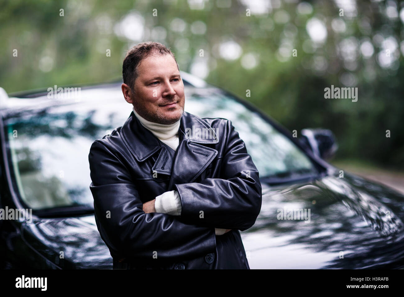 Businessman in leather jacket standing near car Stock Photo