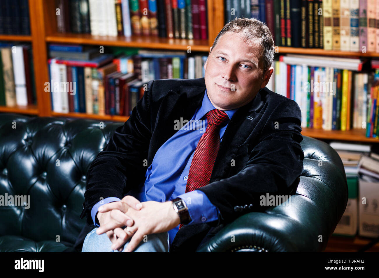 Businessman sitting in the coach in his library Stock Photo Alamy