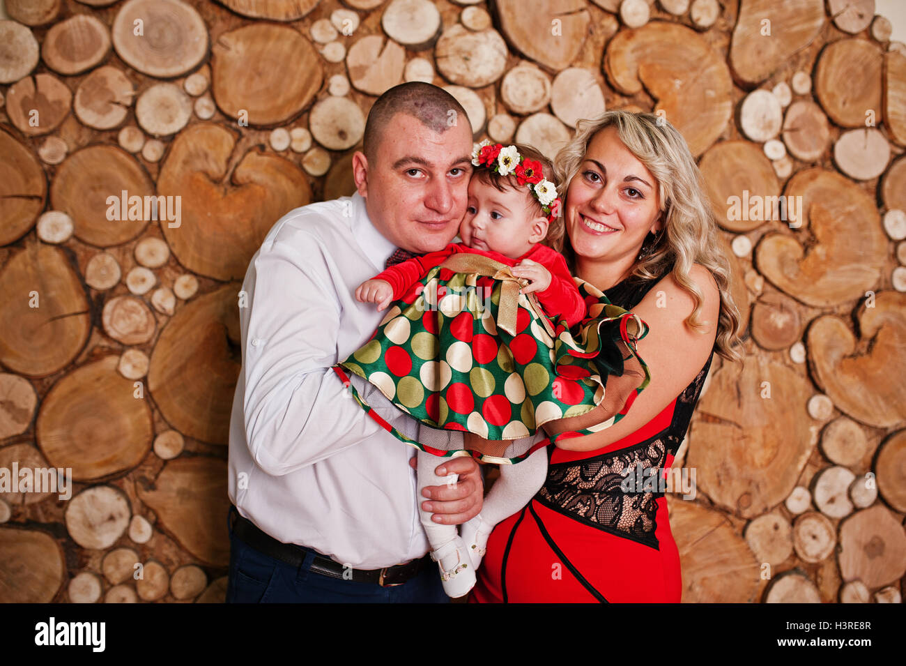 Father and mother with baby daughter posed at studio room Stock Photo