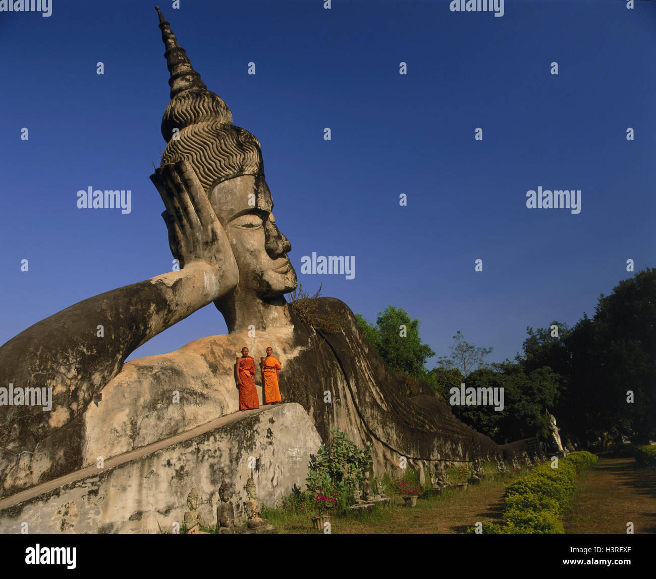 Laos, Vientiane, Wat Kieng Khouan Buddha Park, horizontal Buddha, monks Stock Photo