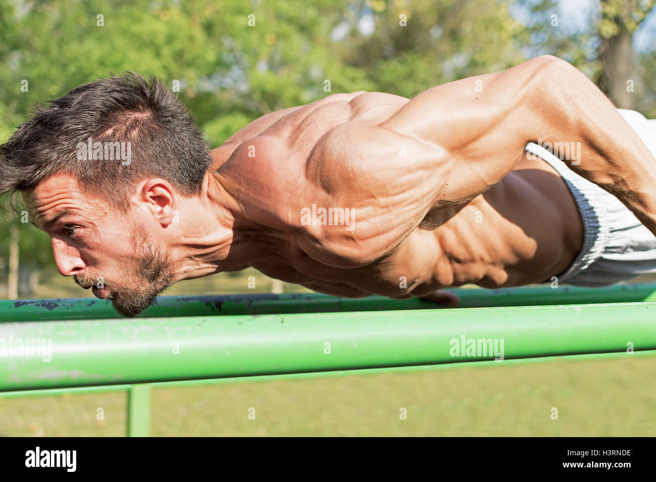 Strong Athletic Man Working Out in an Outdoor Gym. Street Workout Exercises. Tense Muscles. Extreme Sports. Stock Photo