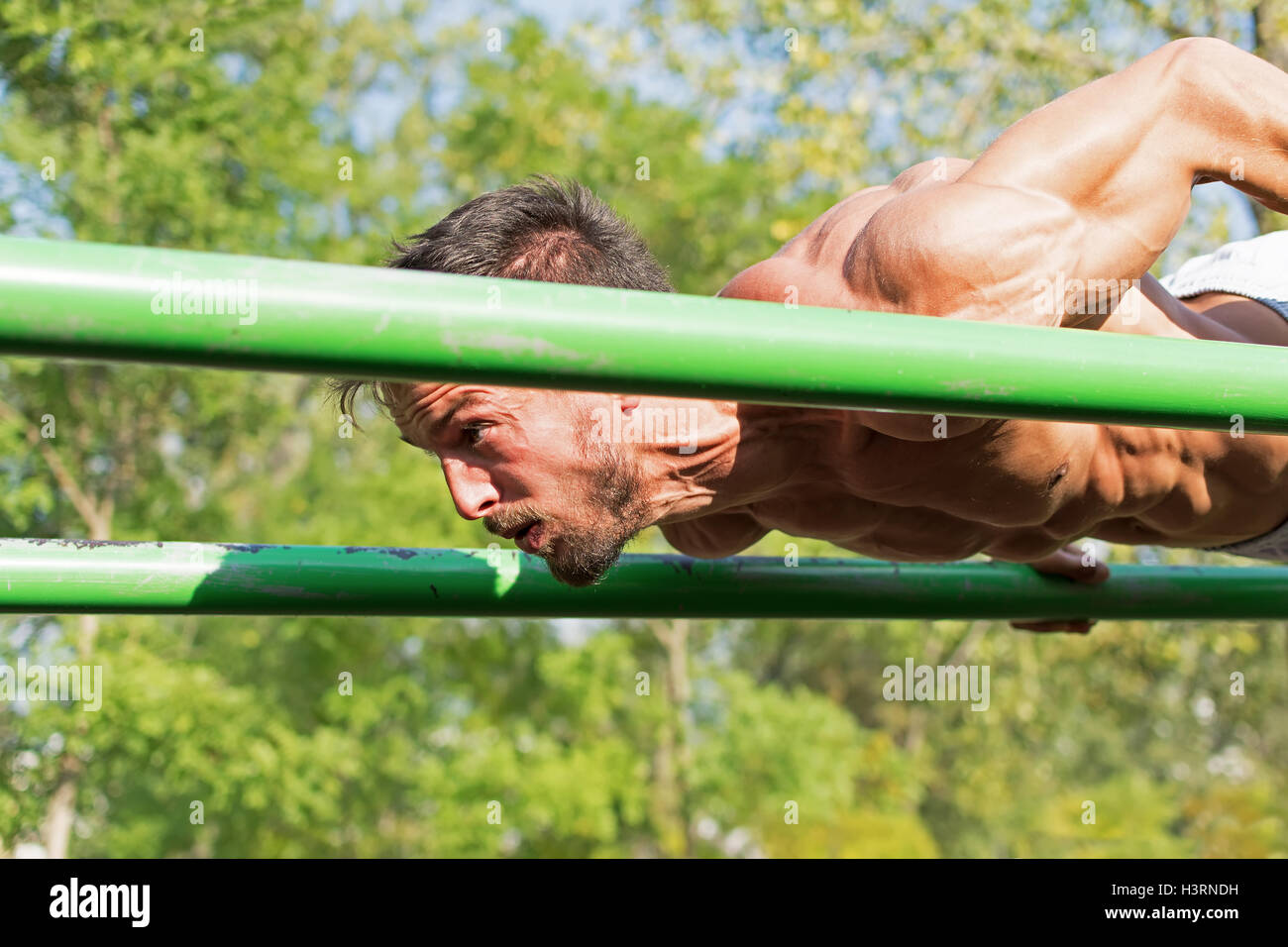 Strong Athletic Man Working Out in an Outdoor Gym. Street Workout Exercises. Tense Muscles. Extreme Sports. Stock Photo