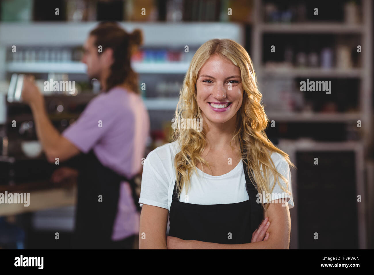 Portrait of smiling waitress standing with arms crossed Stock Photo - Alamy