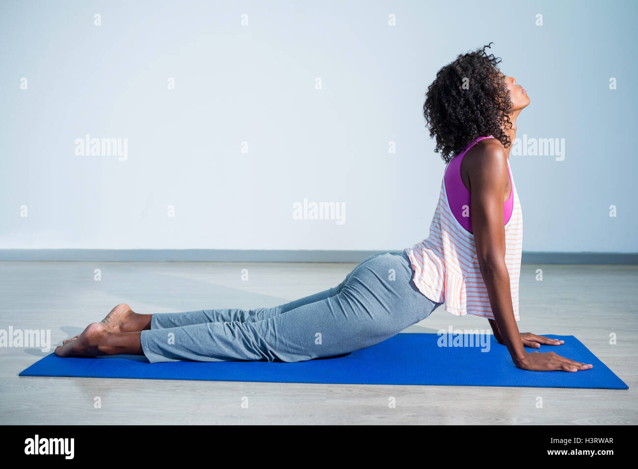 Side view of woman doing core stretch on fitness mat. Young female in  sportswear practicing Cobra pose yoga asana at gym Stock Photo - Alamy