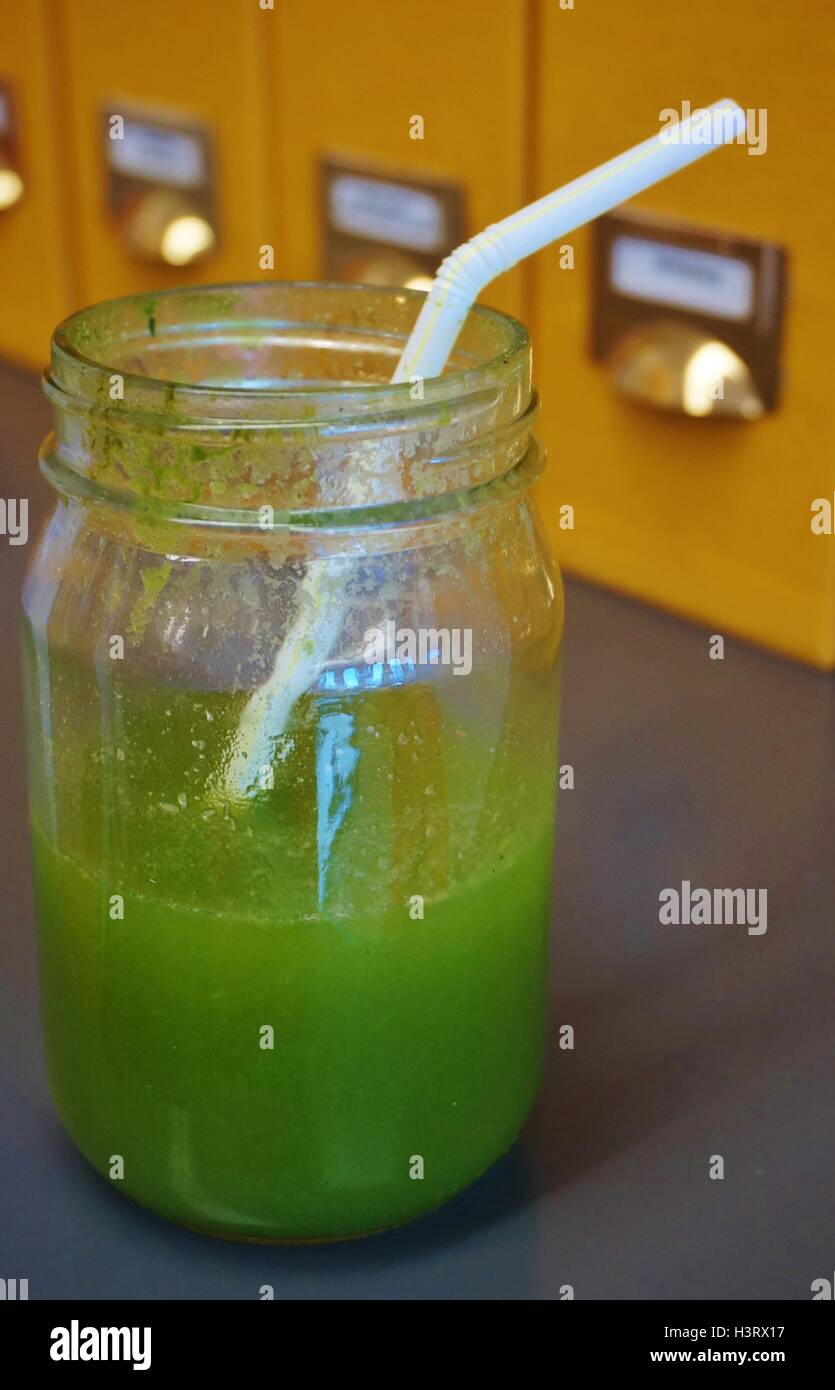 A green kale mojito smoothie in a jar on a desk in an office Stock Photo
