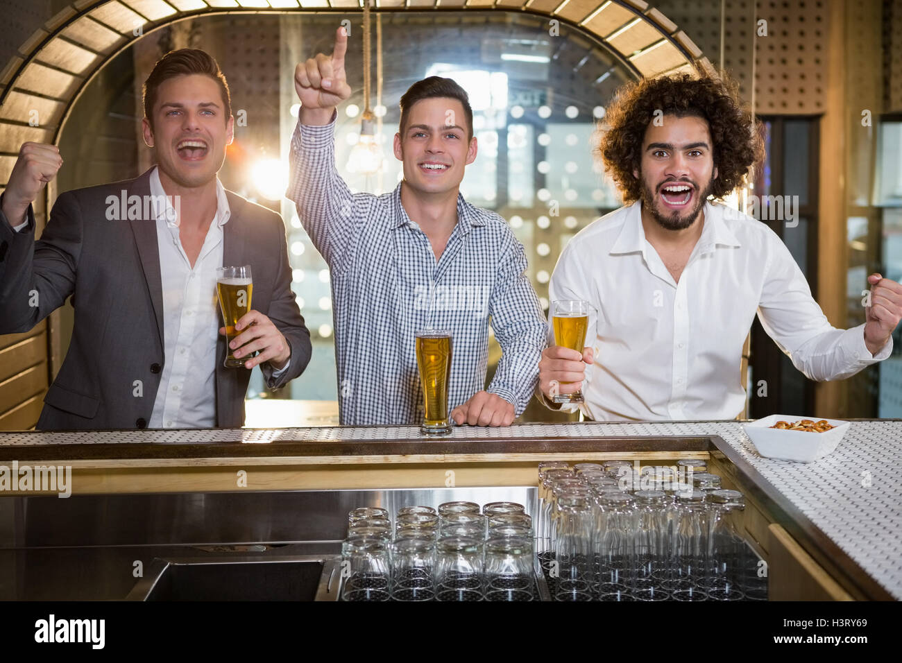 Friends raising their fist while having beer at bar counter Stock Photo