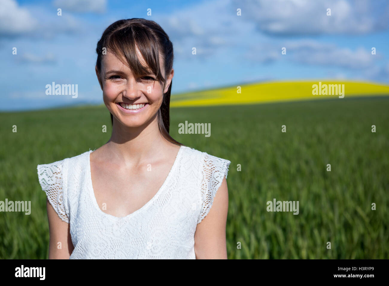 Happy young woman standing in field Stock Photo - Alamy