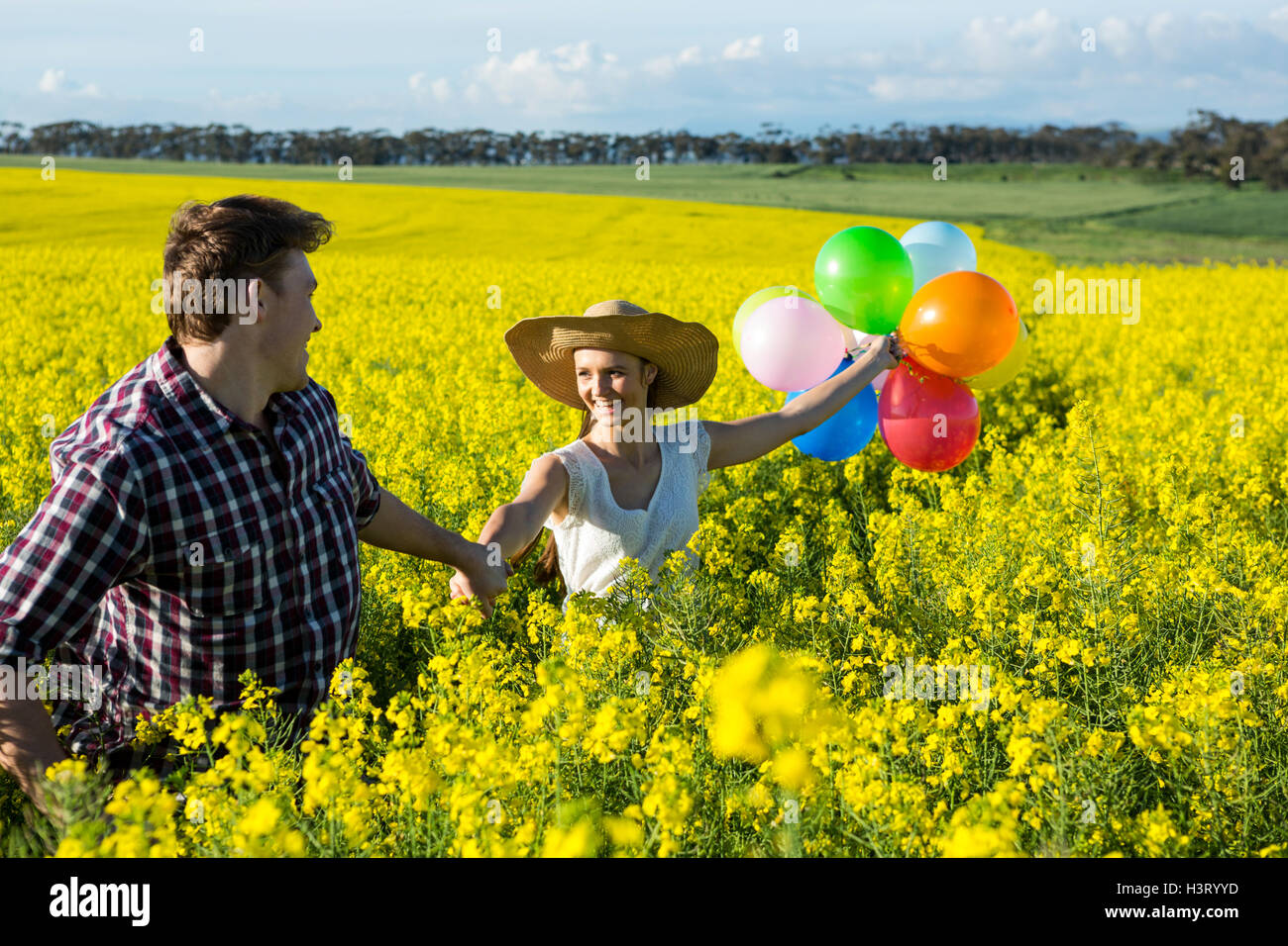 Couple holding colorful balloons in mustard field Stock Photo - Alamy