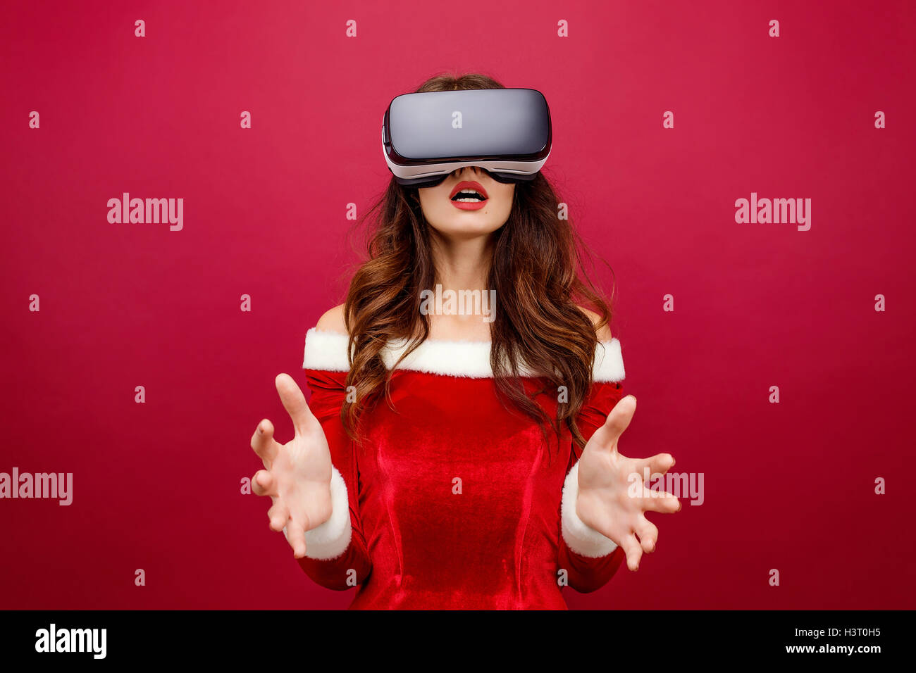Portrait of young brunette woman in red velvet dress using virtual reality headset Stock Photo