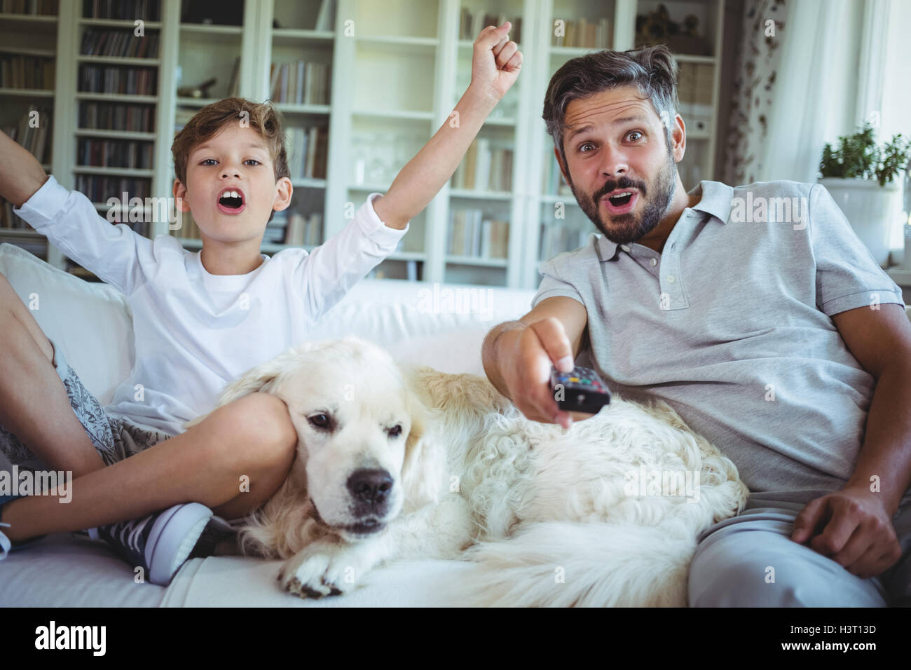 Father and son sitting on sofa with pet dog and watching television Stock  Photo - Alamy