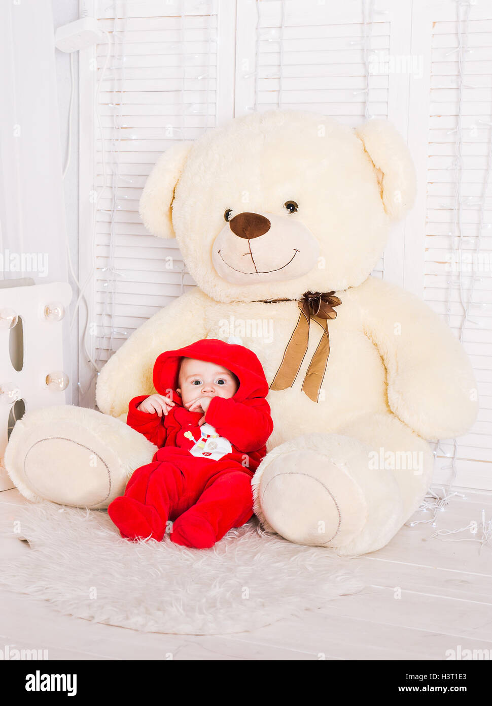 Cute baby with big teddy bear on white room Stock Photo - Alamy