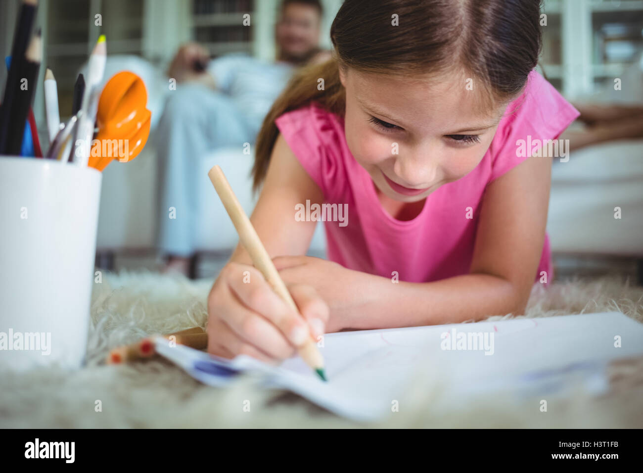 Smiling girl lying on the floor and drawing Stock Photo - Alamy