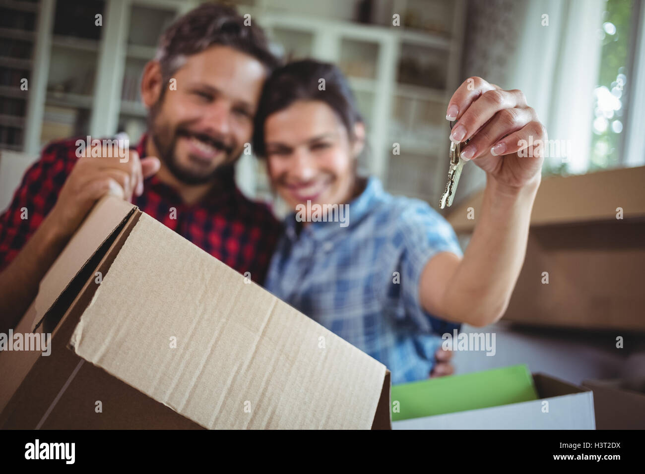 Smiling couple holding keys in their new house Stock Photo - Alamy