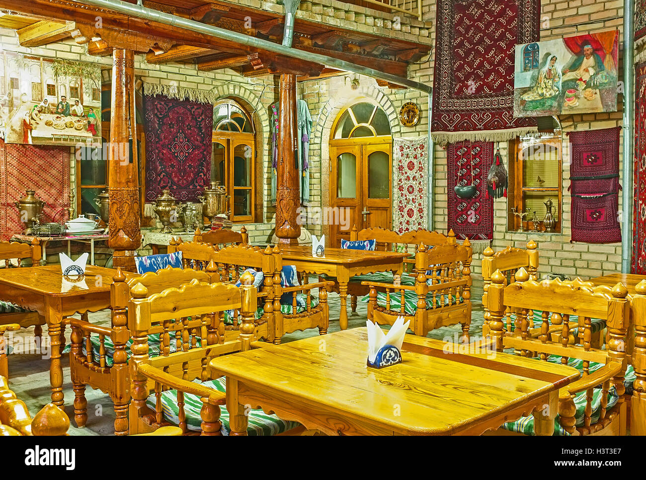 The traditional teahouse decorated with the silk carpets on the walls in Bukhara. Stock Photo