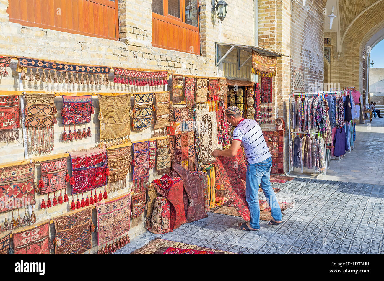 The rug merchant lay out the carpets next to his stall in Bukhara. Stock Photo