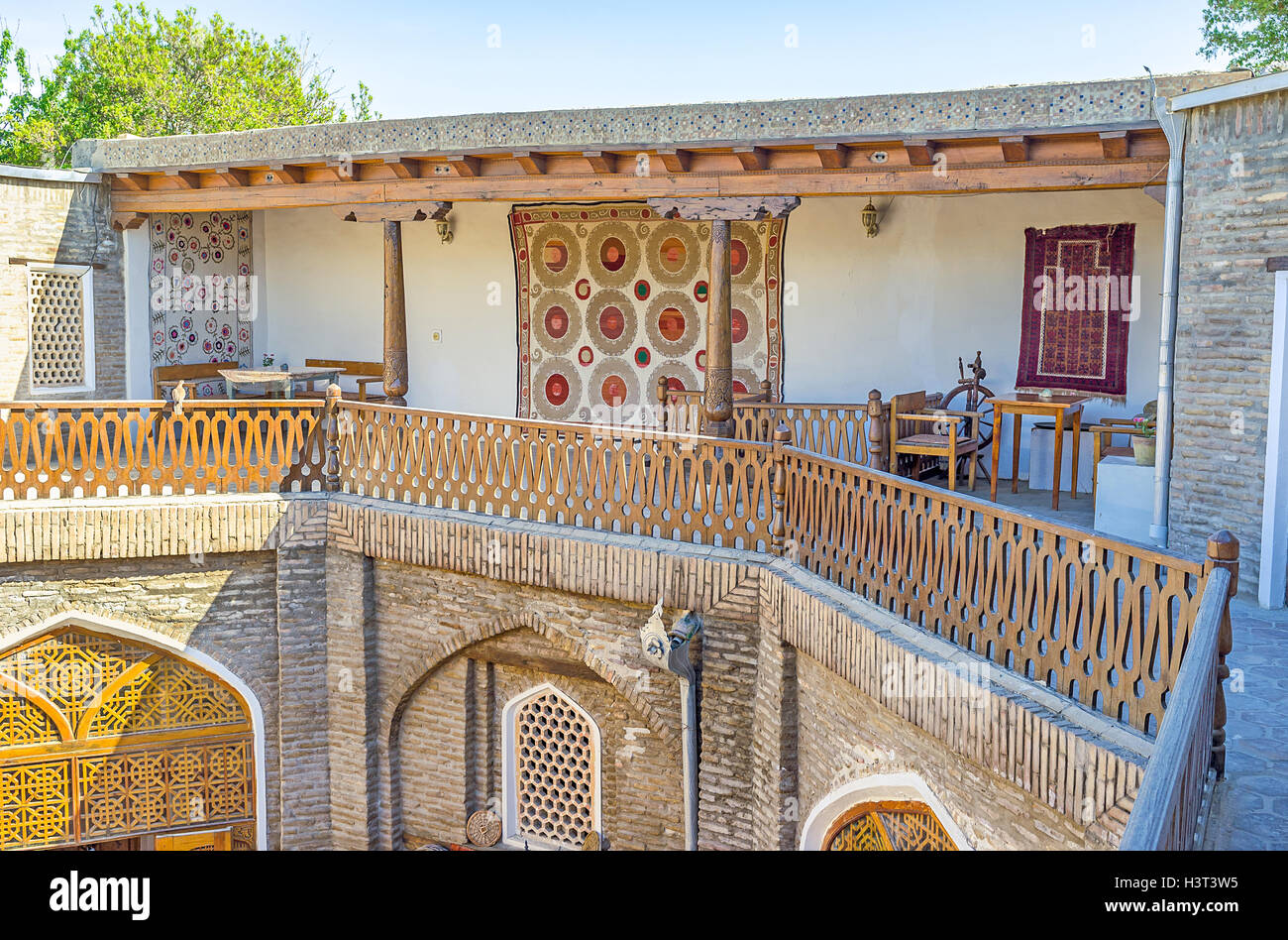 The terrace in old Caravan Saray is decorated with the silk carpets, made in traditional style, Bukhara, Uzbekistan. Stock Photo