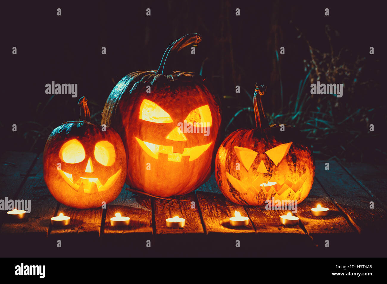 Halloween pumpkins head jack lantern with candles around on the old boards in a spooky night landscape. Soft focus. shallow DOF Stock Photo