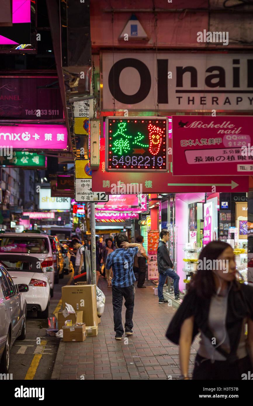 People walking at a sidewalk at the Hennessy Road in Causeway Bay, Hong Kong at night. Stock Photo
