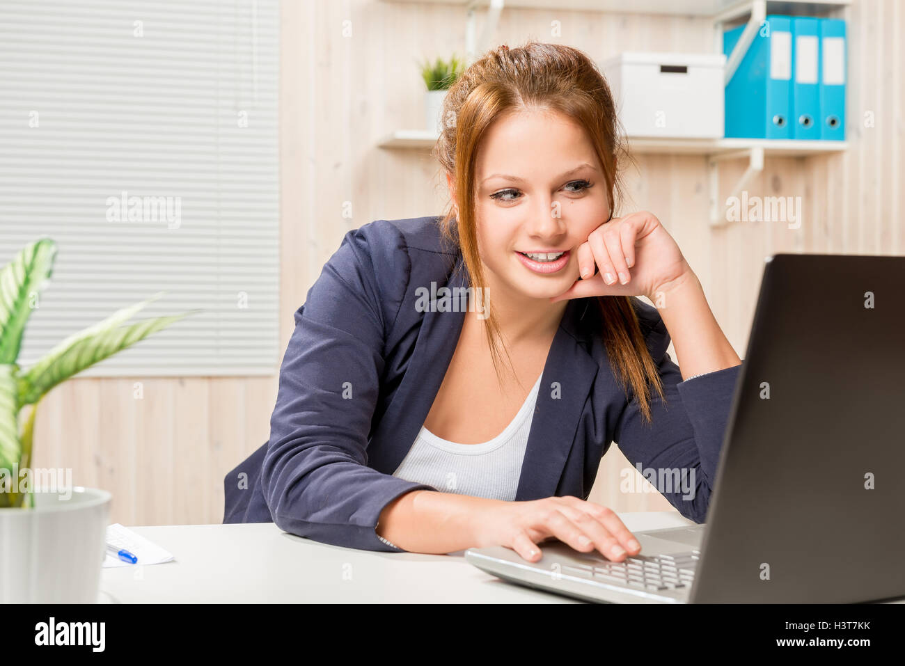 girl in the office in a good mood works on a computer Stock Photo