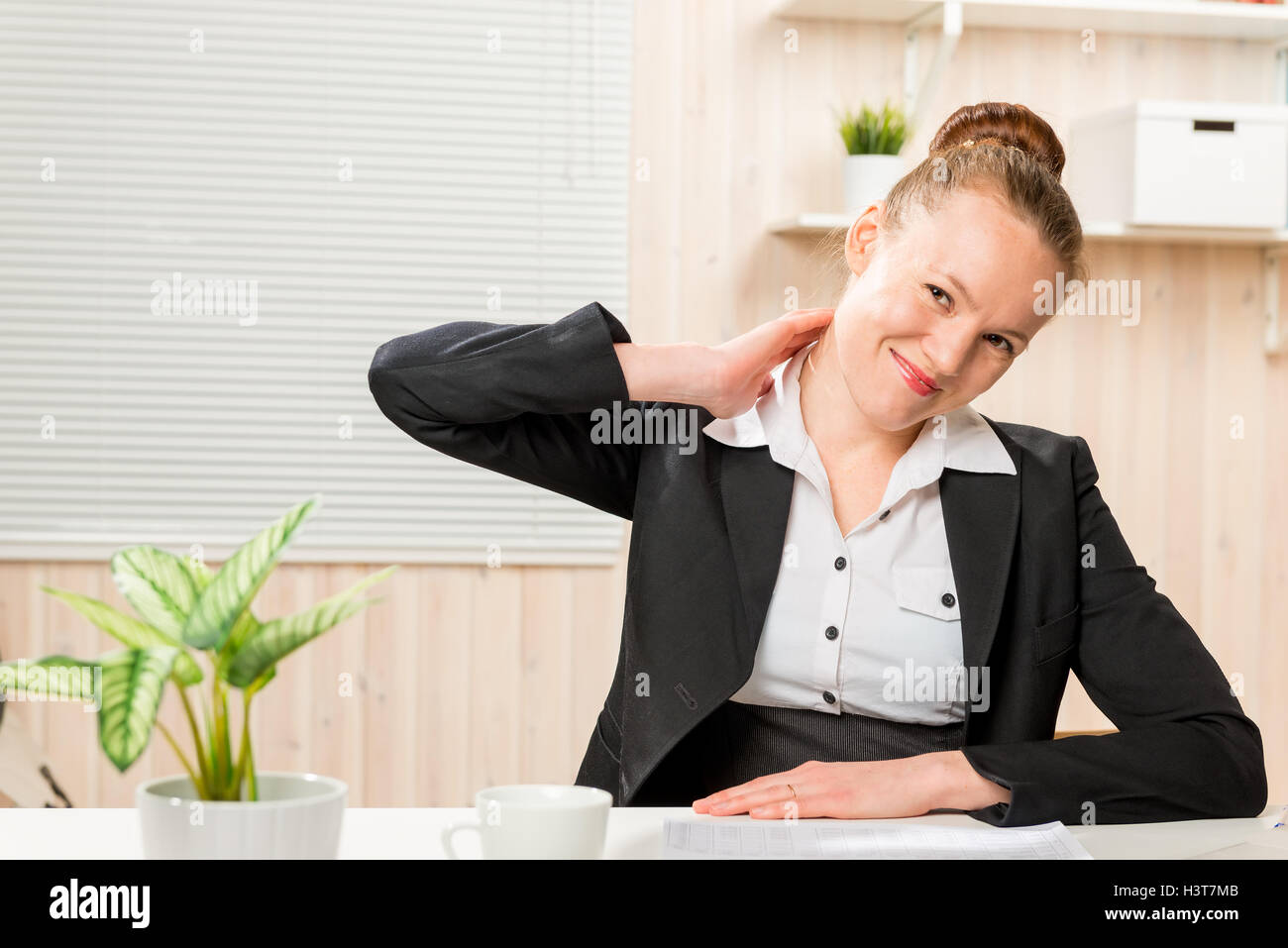 woman in a business suit rubbing his neck, which is sore from working at a computer Stock Photo