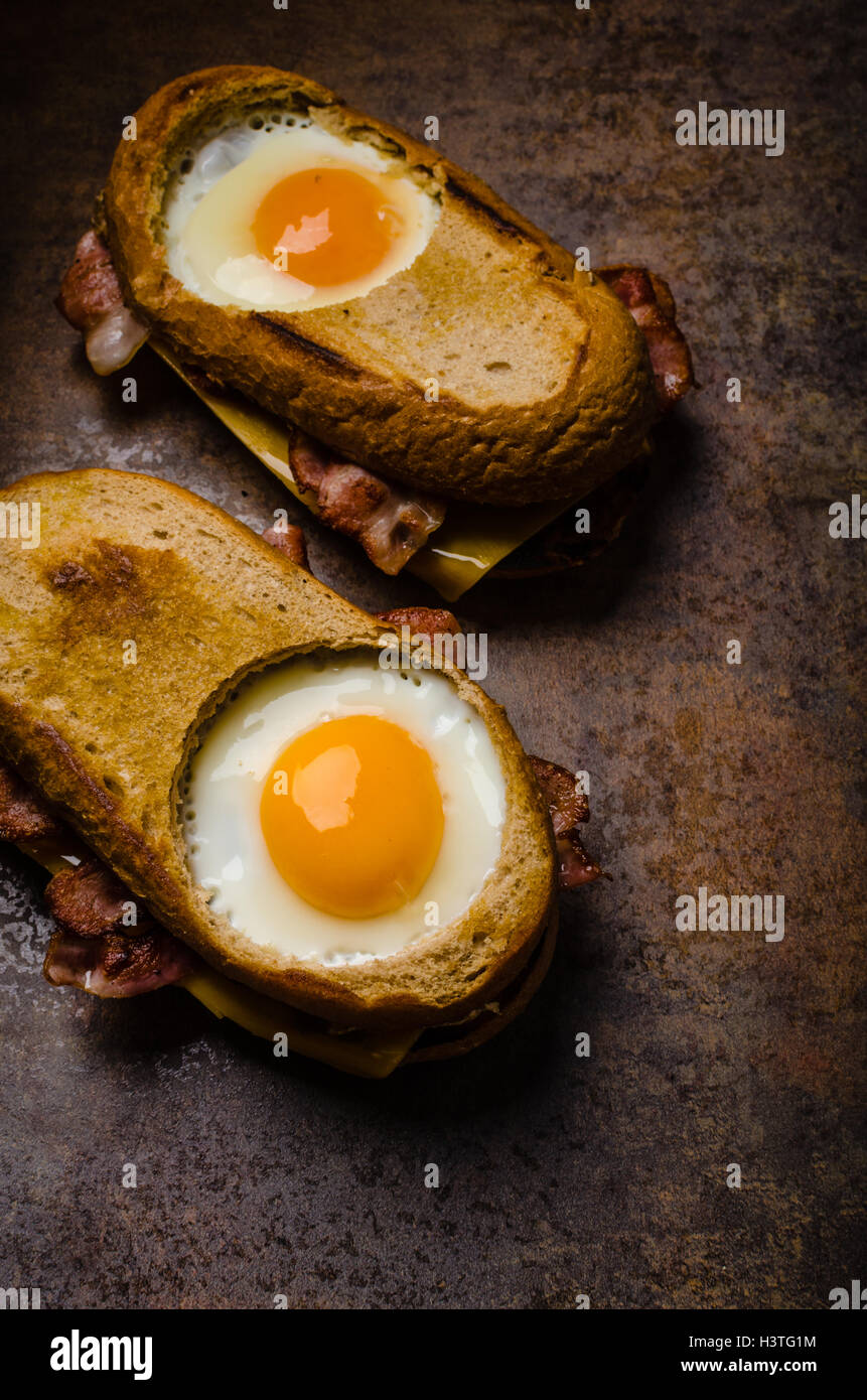 Toasted bread with cheddar cheese and crispy bacon, fried egg inside ...