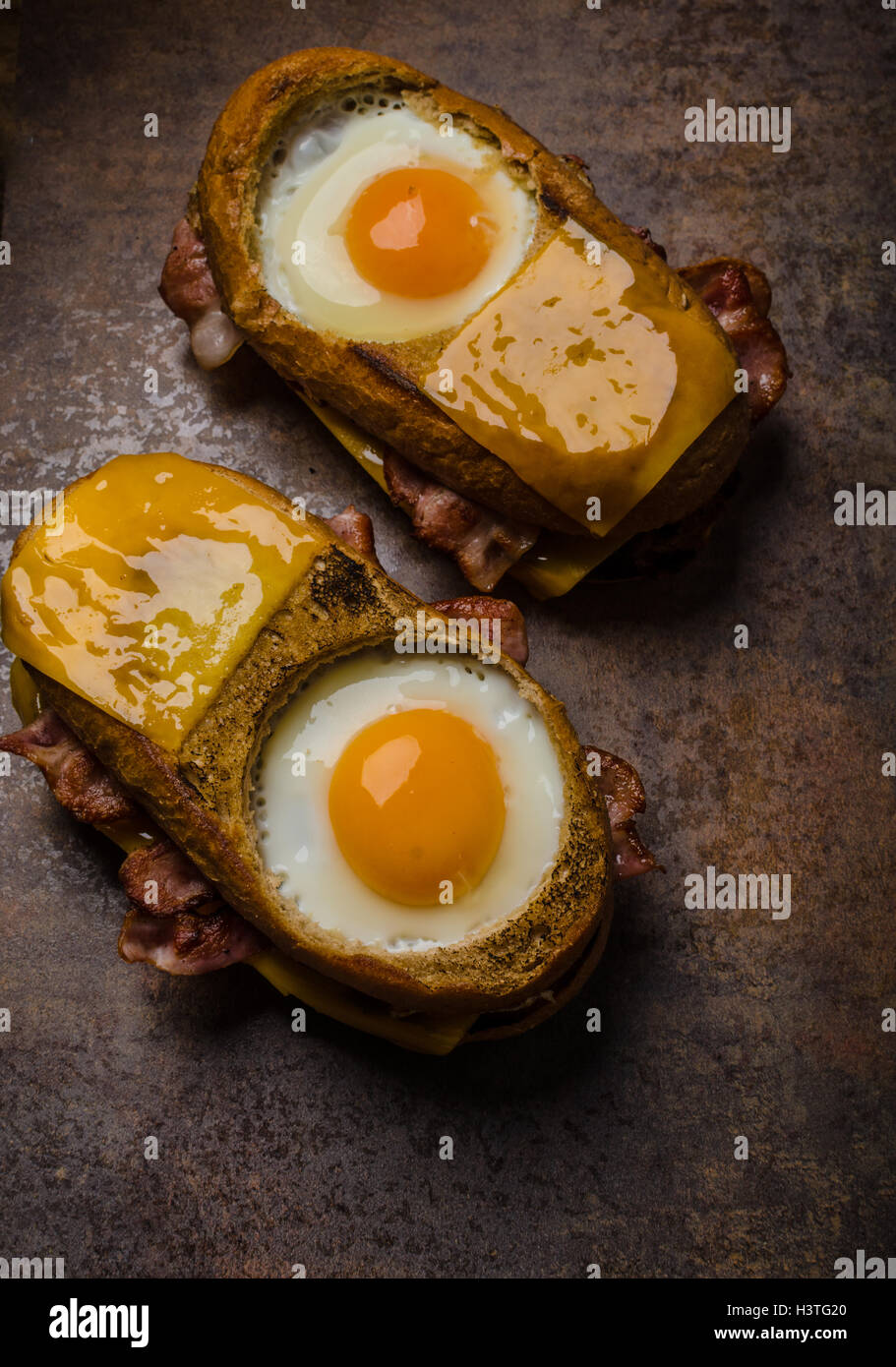 Toasted bread with cheddar cheese and crispy bacon, fried egg inside ...