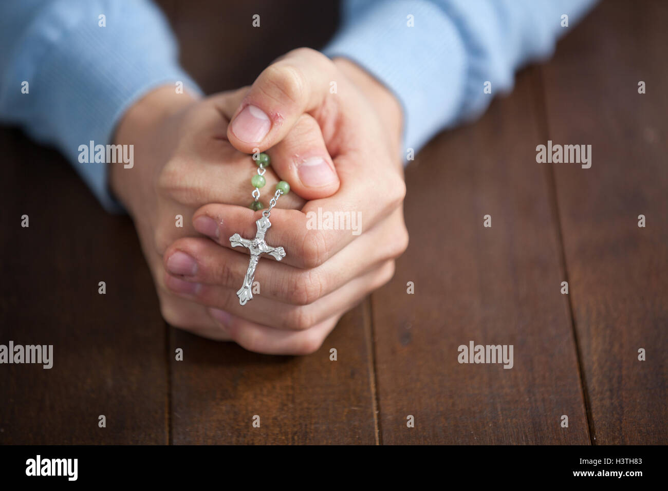 Praying hands of man with a rosary Stock Photo