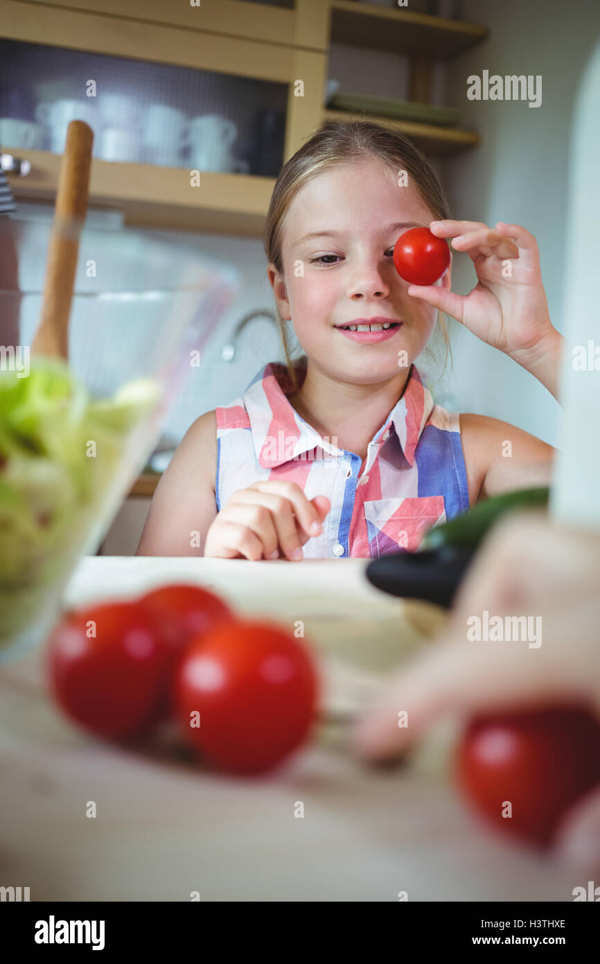 Playful girl holding cherry tomato on her eye Stock Photo - Alamy