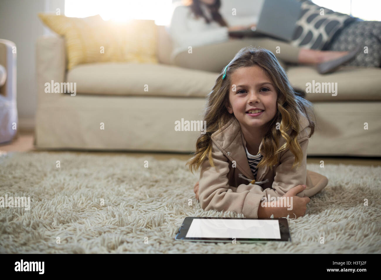 Girl using digital tablet while lying on the floor Stock Photo - Alamy