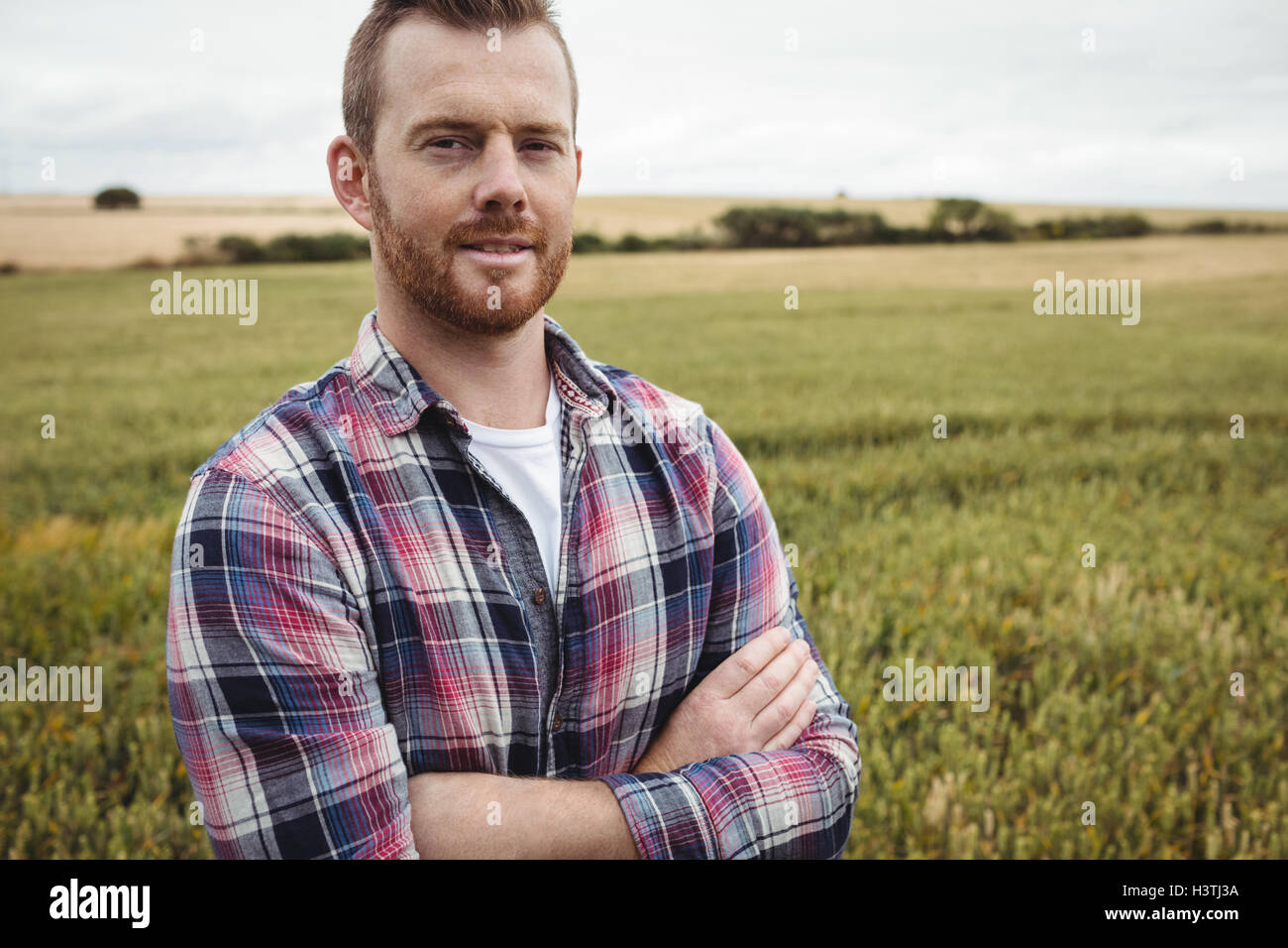 Portrait of farmer standing with arms crossed in the field Stock Photo ...