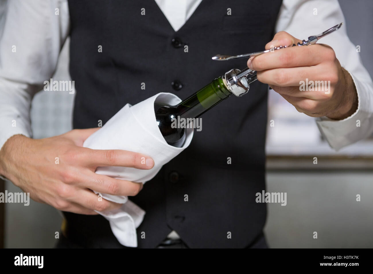 Bartender using corkscrew to open wine bottle Stock Photo Alamy