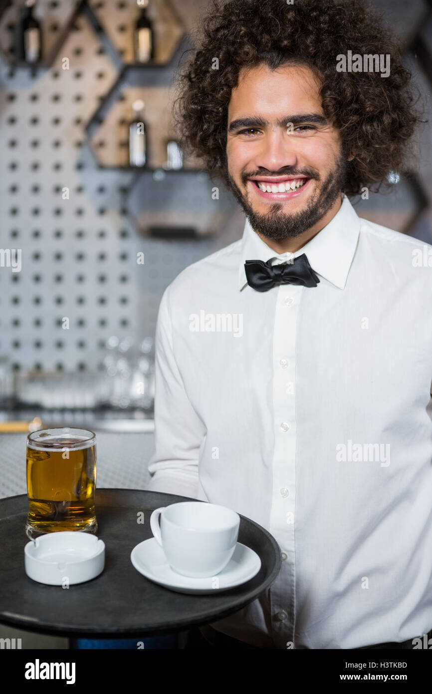 Waiter holding tray of beer glass and tea cup Stock Photo - Alamy