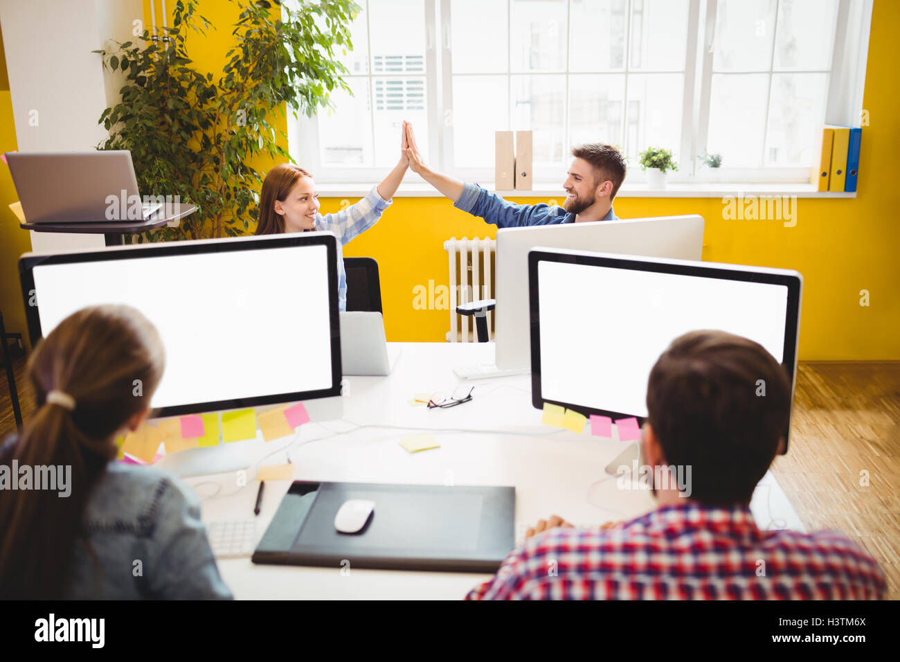 Happy graphic designers giving high-five Stock Photo - Alamy