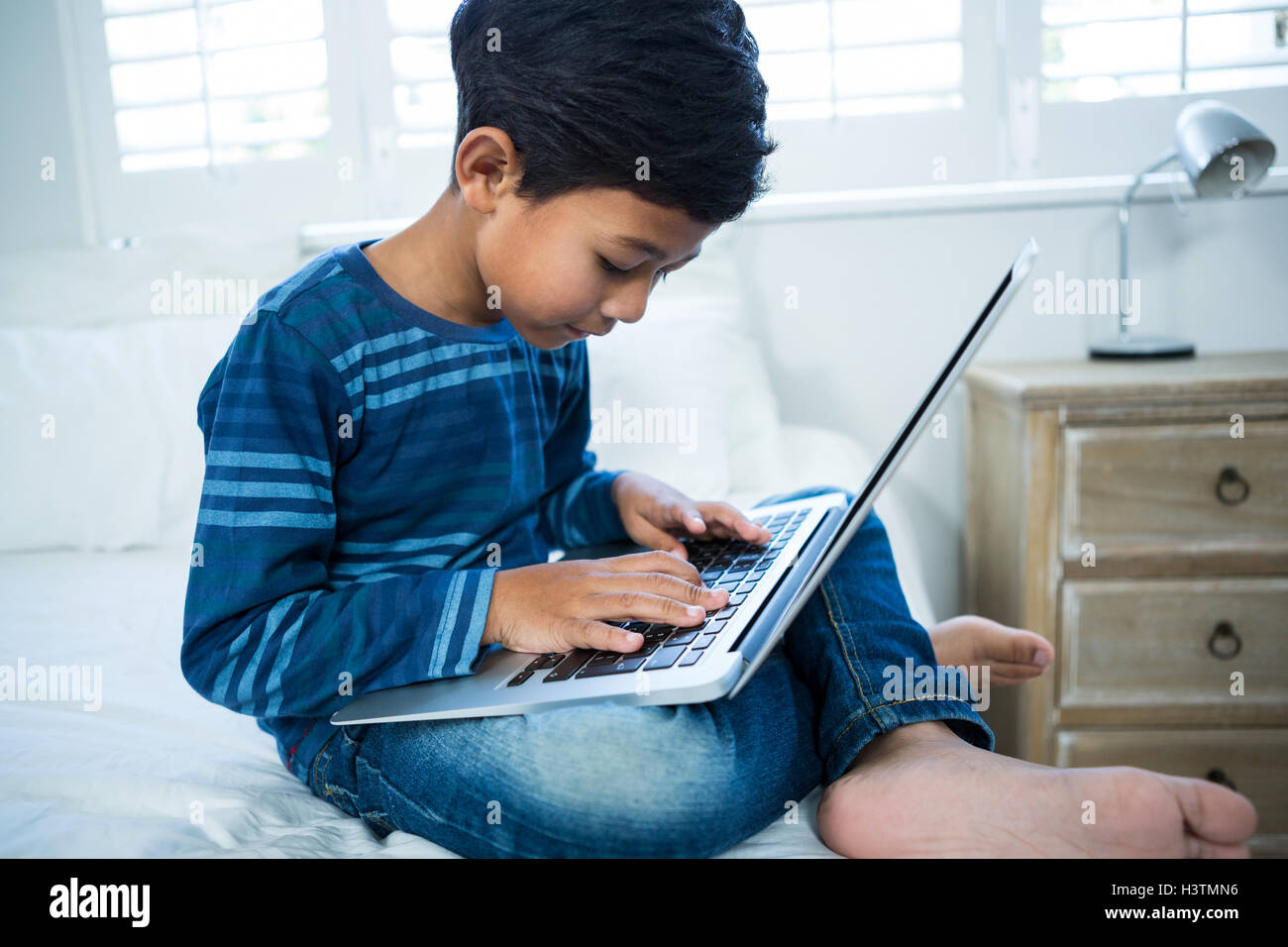 Boy using laptop while relaxing on bed Stock Photo - Alamy