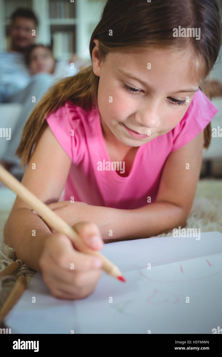 Girl drawing while lying on the floor Stock Photo - Alamy