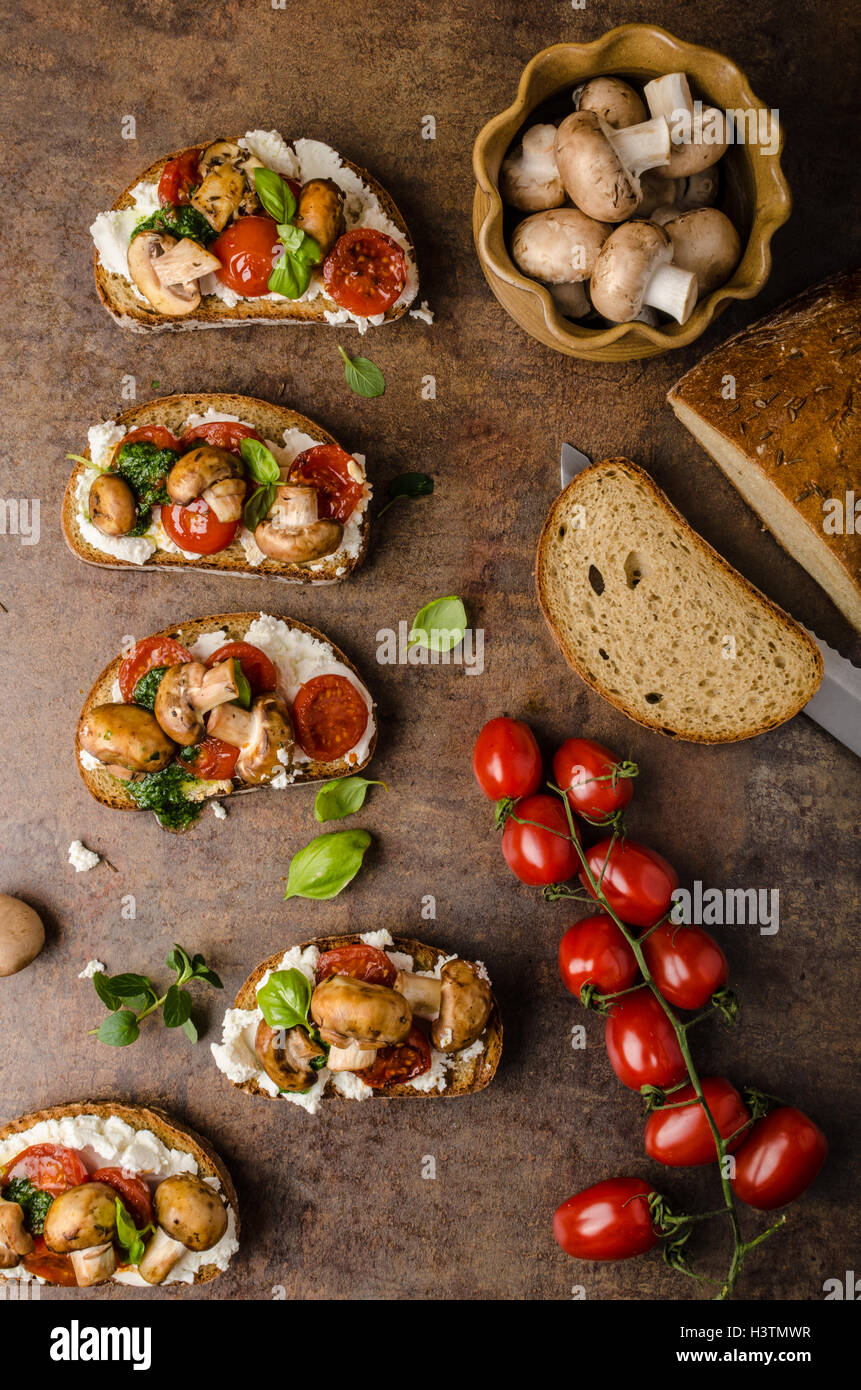 Toasted bruschetta with ricotta, basil pesto and cherry tomatoes