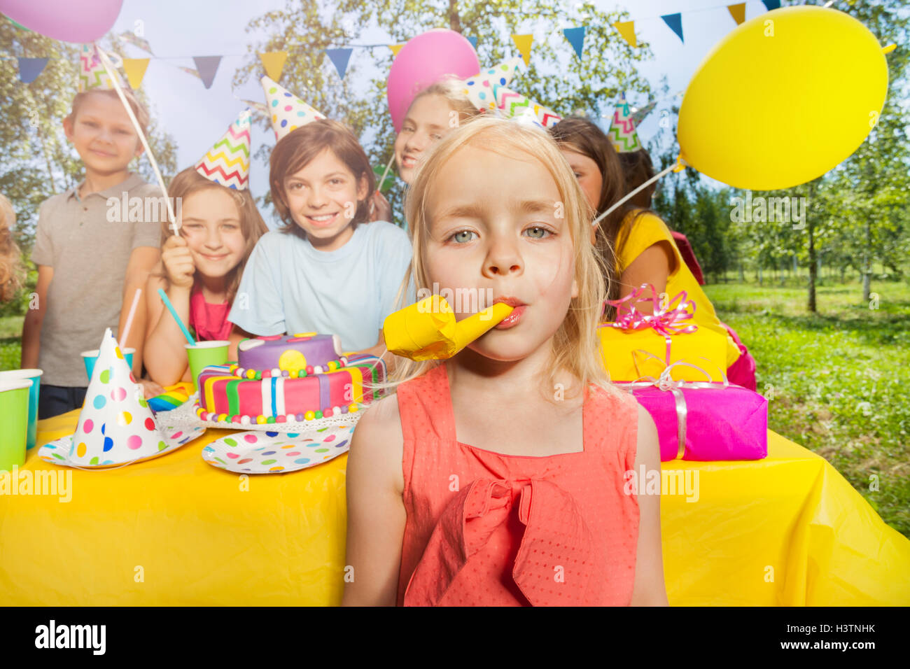 Little adorable girl playing with party blower Stock Photo
