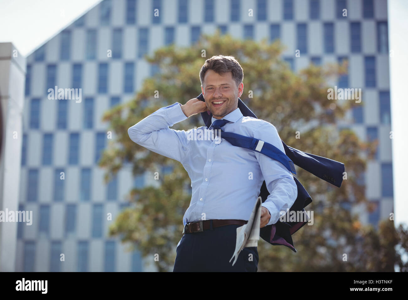 Portrait of businessman holding blazer and newspaper Stock Photo - Alamy