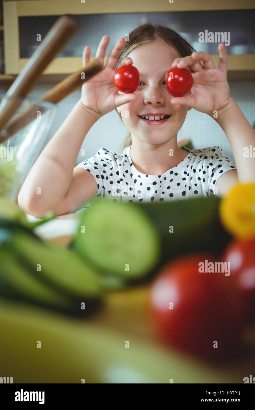 Playful girl holding cherry tomato on her eye Stock Photo - Alamy