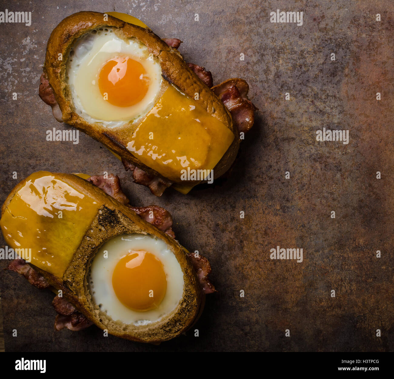 Toasted bread with cheddar cheese and crispy bacon, fried egg inside ...