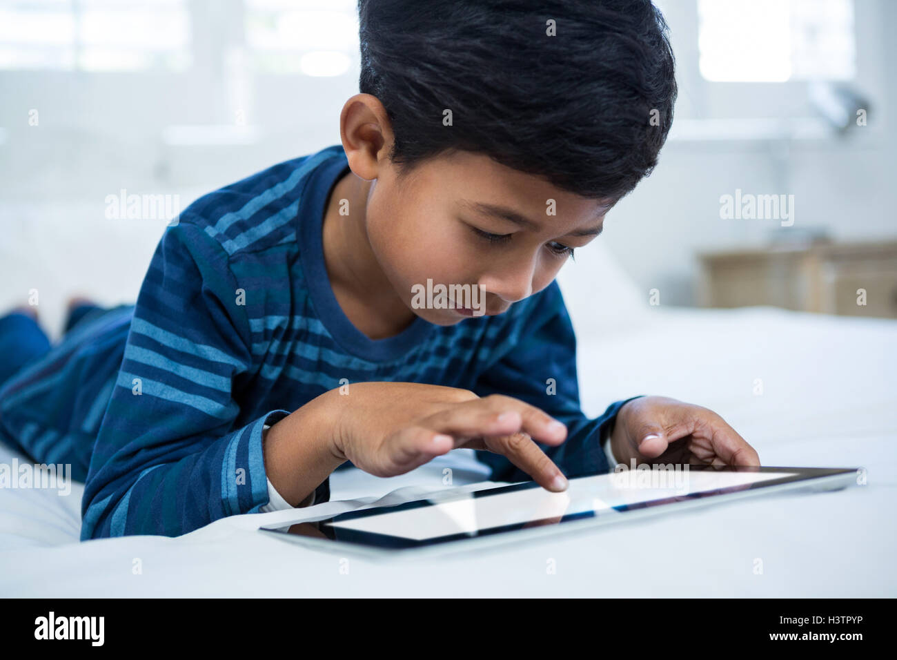 Boy using digital tablet while relaxing on bed Stock Photo - Alamy