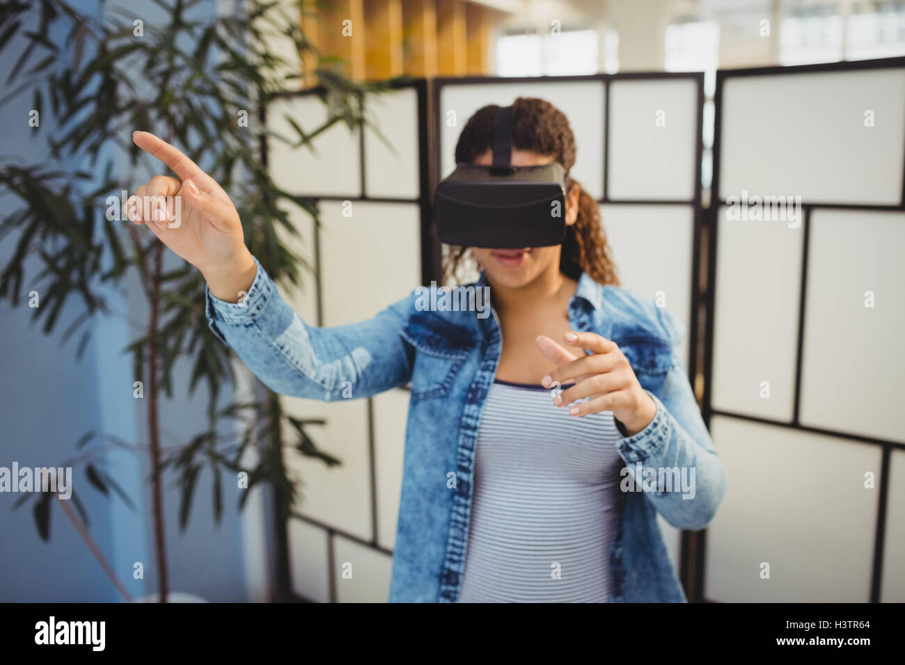 Businesswoman pointing while using virtual reality headset Stock Photo ...