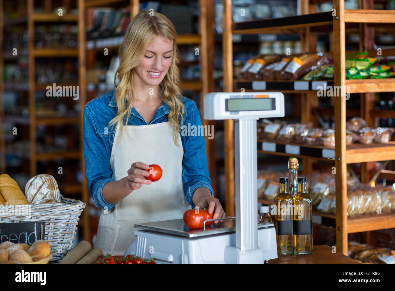 Female staff weighting vegetables on scale Stock Photo