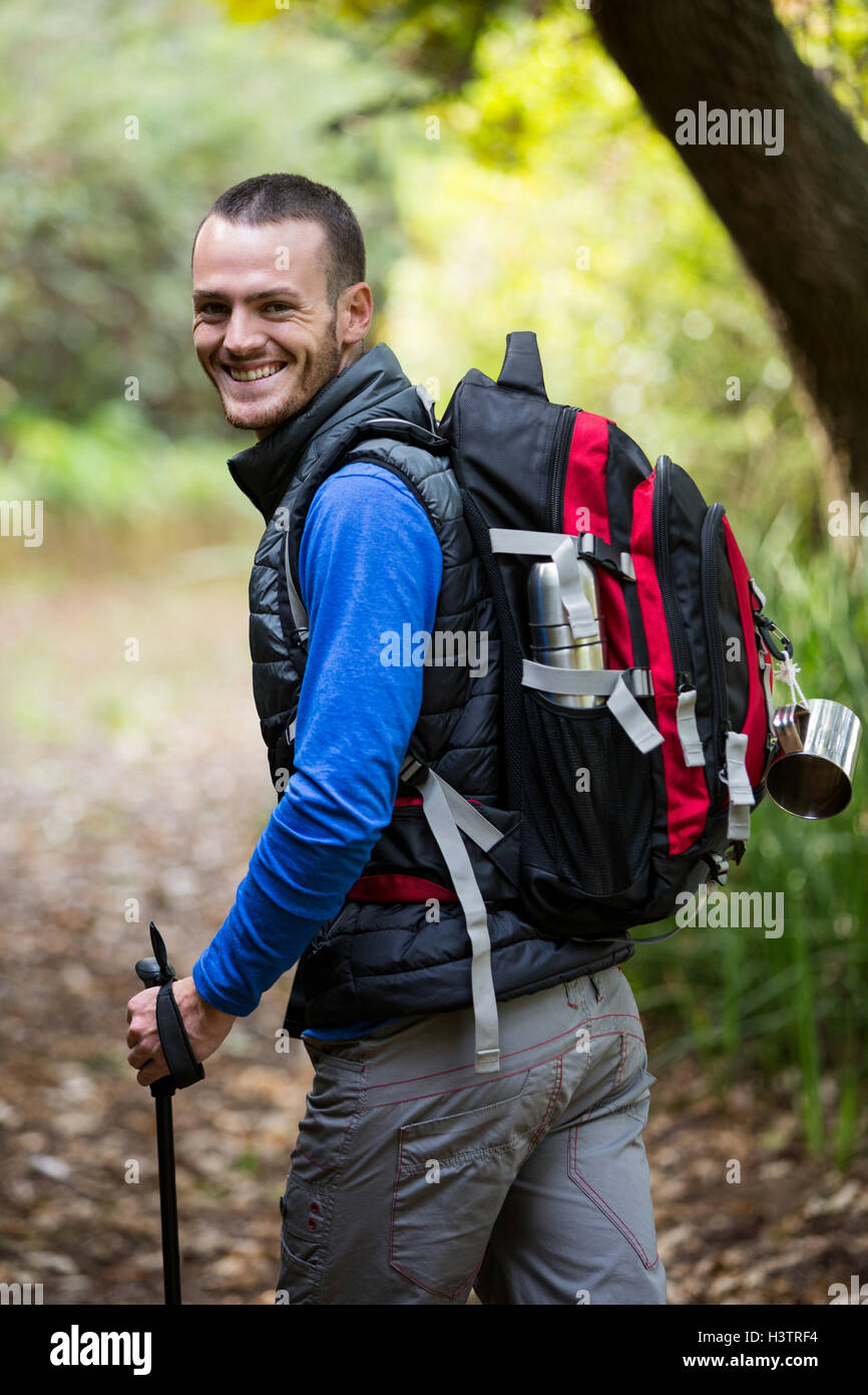 Smiling male hiker walking with hiking pole Stock Photo