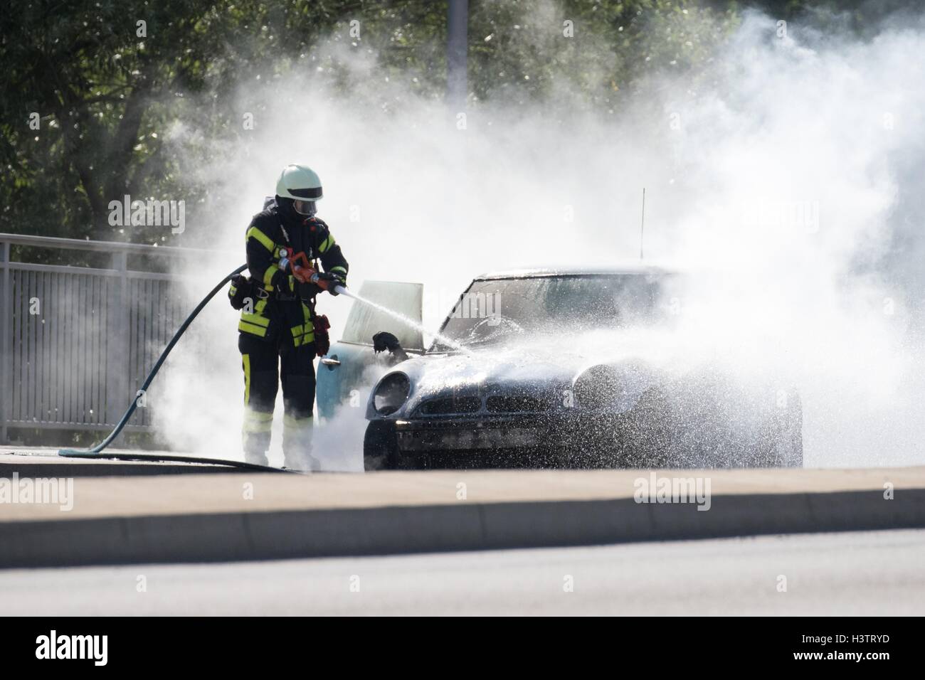 Firefighter extinguishes burning car, Germany Stock Photo Alamy